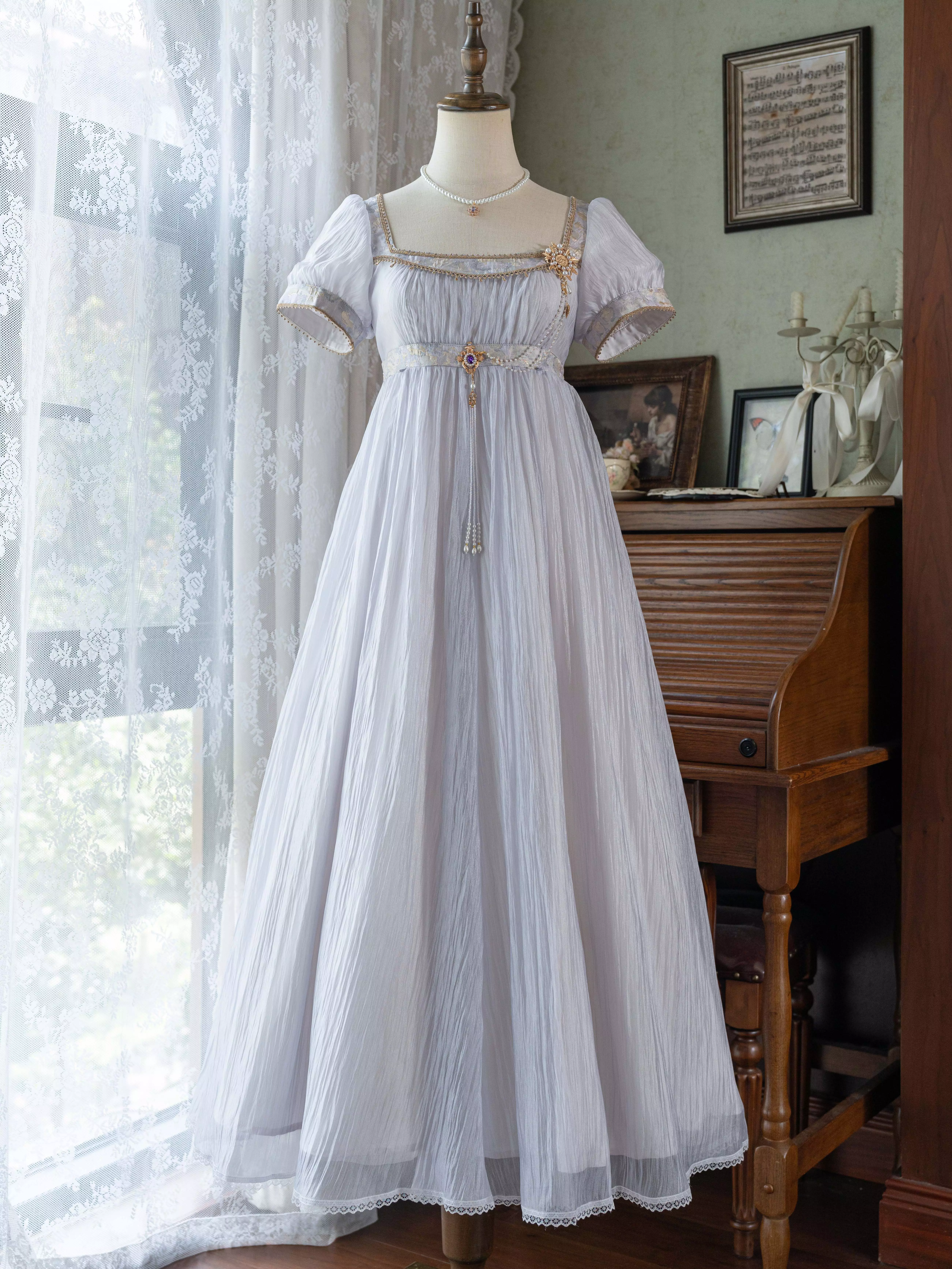 Front full-length view on mannequin of light purple Regency Lolita dress with square puff sleeves, sheer wrinkled polyester fabric, empire waist, gold waist trim