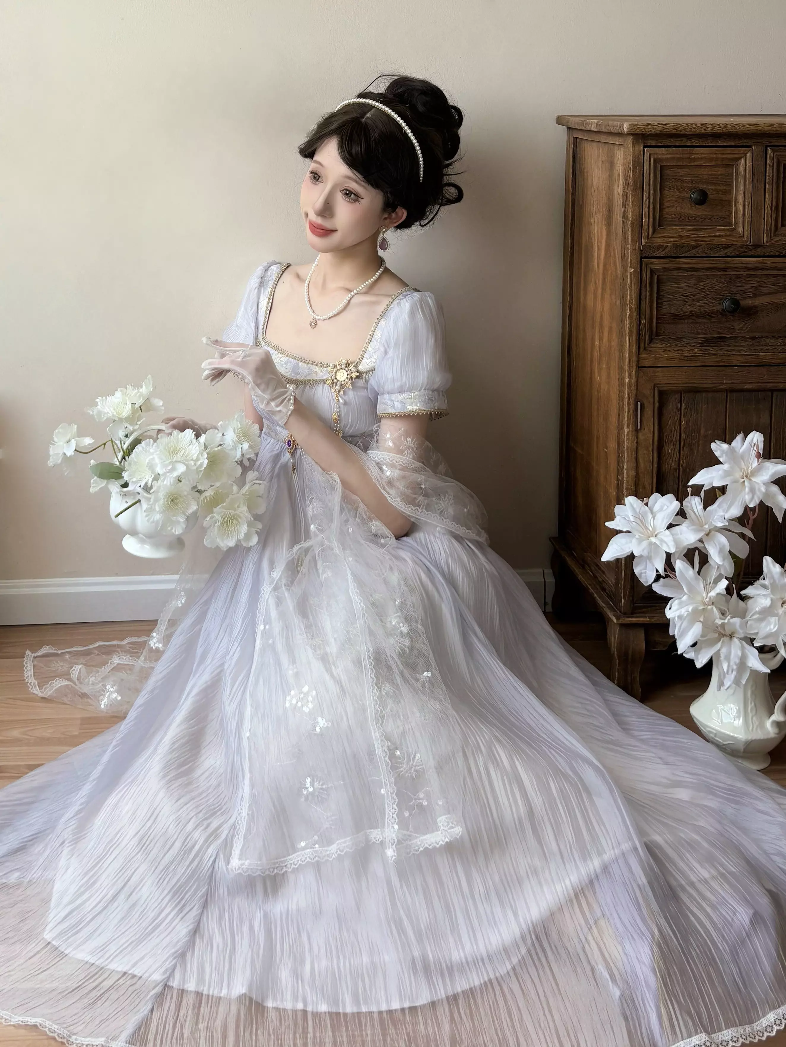 Seated low-angle view of purple Regency Lolita wedding gown with square puff sleeves, empire waist, long floor-length skirt with train, holding flower bouquet
