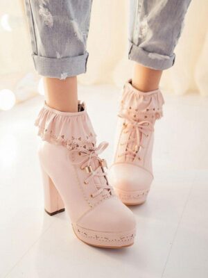 Pale pink Lolita platform ankle boots with ruffled lace cuff worn on feet with rolled-up cropped jeans, front-on view showcasing chunky heel and lace-up fastening detail