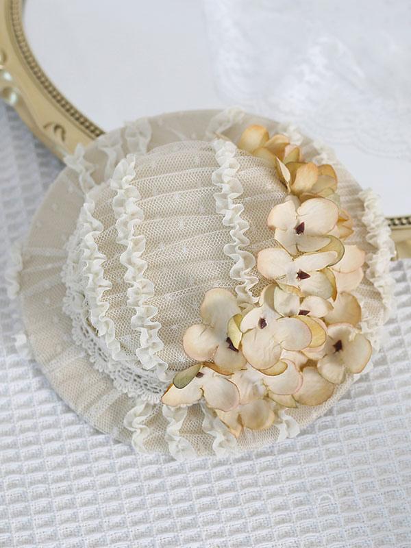 Overhead view of cream-colored pleated mesh Lolita hat with cream yellow hydrangea blooms and delicate lace trim edges