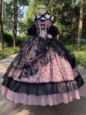 Pink and black gothic Lolita JSK ball gown with cross halter corset bodice and 3D floral accents displayed on dress mannequin in outdoor park setting