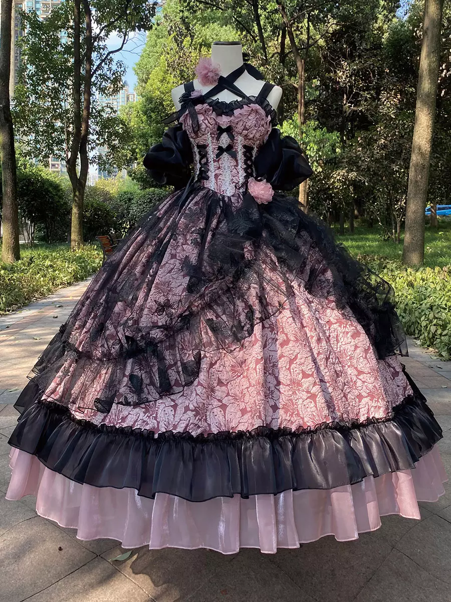 Pink and black gothic Lolita JSK ball gown with cross halter corset bodice and 3D floral accents displayed on dress mannequin in outdoor park setting
