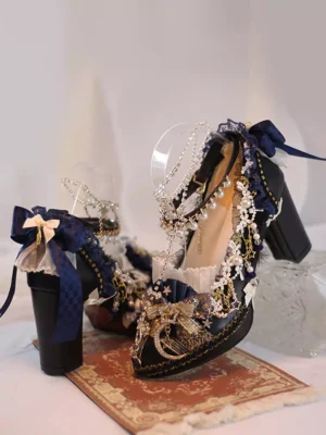Black lolita chunky heel pumps with navy blue bow and gold chain trims shown in elegant three-quarter side view on vintage rug backdrop