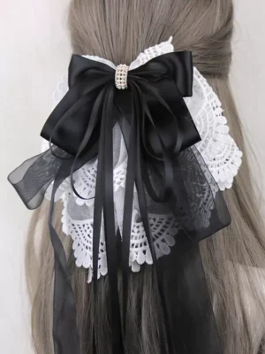Sweet lolita bow hair clip with black satin bow, white lace ruffles, and rhinestone center worn on light brown mannequin hair back view