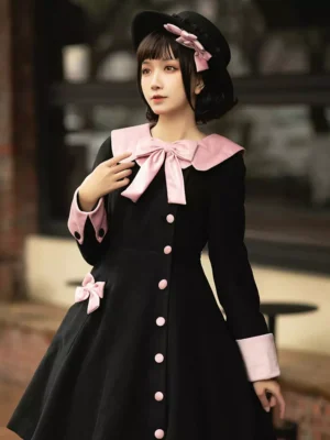 Black and pink rococo lolita overcoat front view with sailor collar, pink buttons, and bow details on model wearing bowler hat outdoor vintage street style