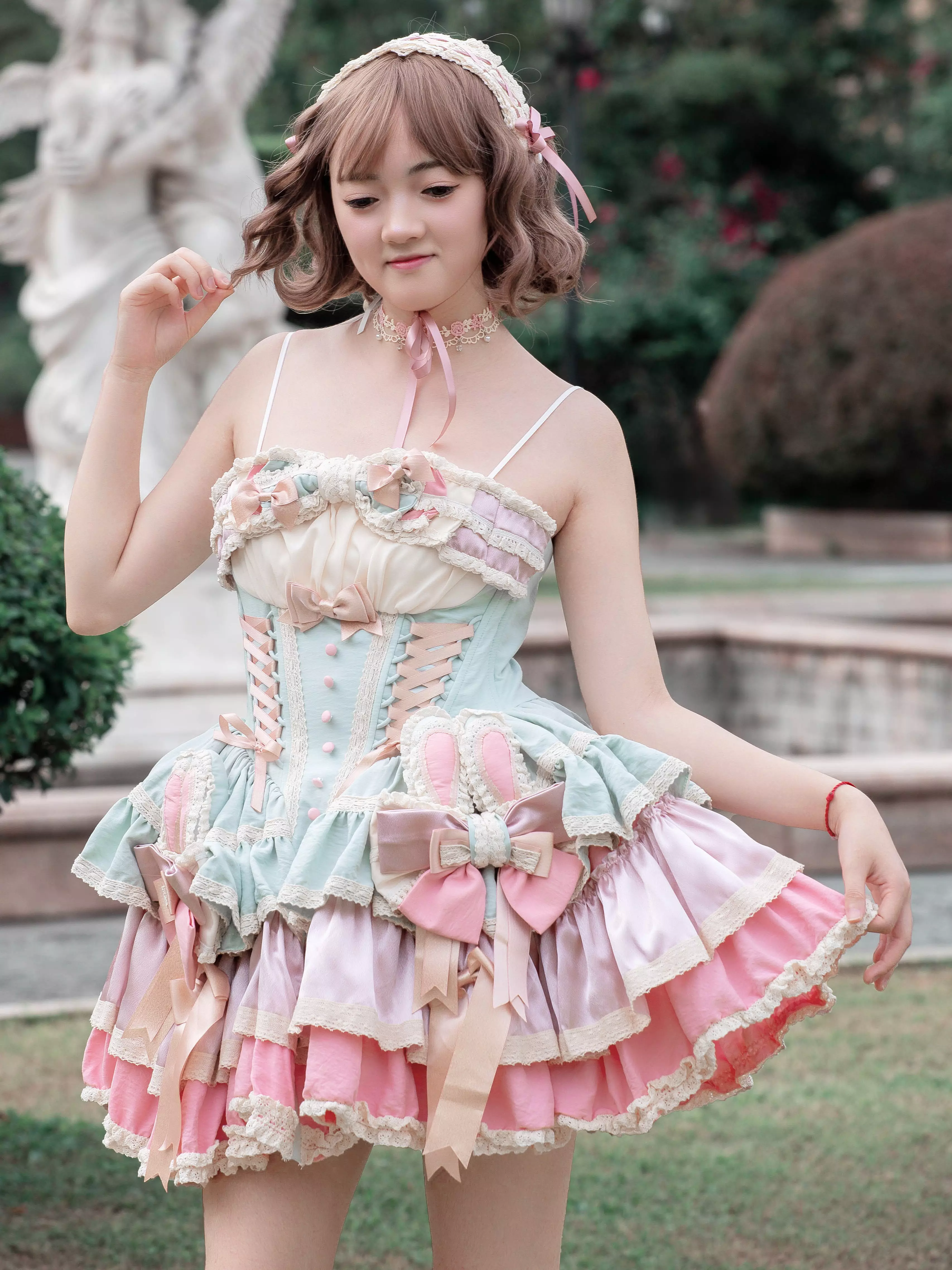 Half-body outdoor view of model wearing sweet lolita fairy dress with matching hair accessory ruffled skirt and corset-style bodice