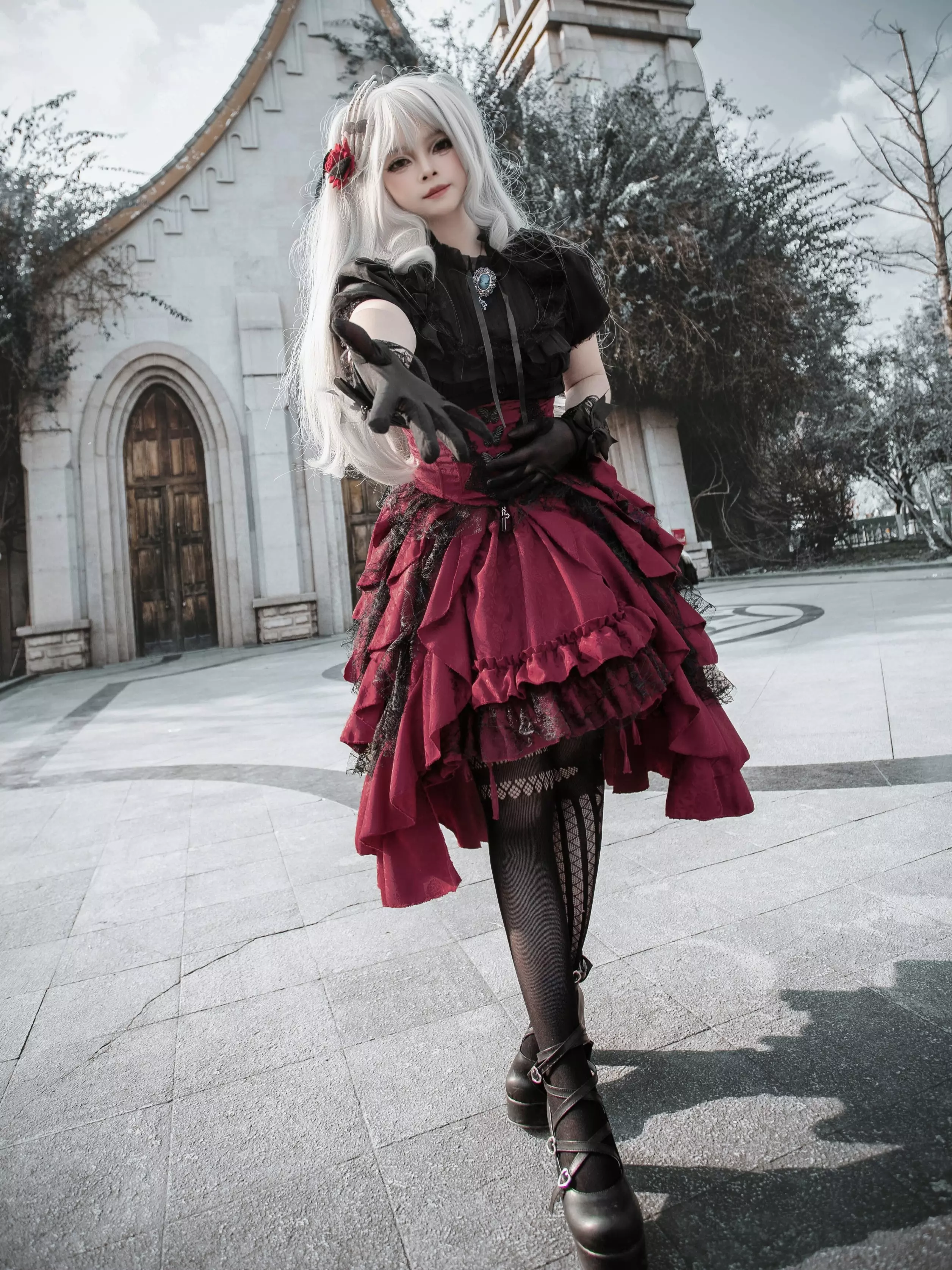 Gothic lolita dress front view showing black jacquard lace short-sleeve top and wine-red short ruffle skirt with fishnet stockings and dramatic silhouette
