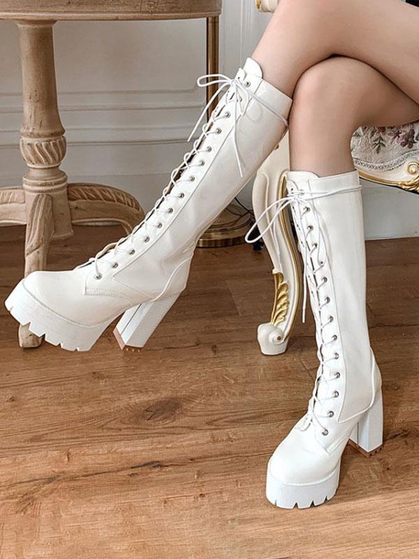 White platform lace-up mid-calf boots with round toe and chunky heel, worn by model on wooden floor, three-quarter side view showing lolita fashion boot styling