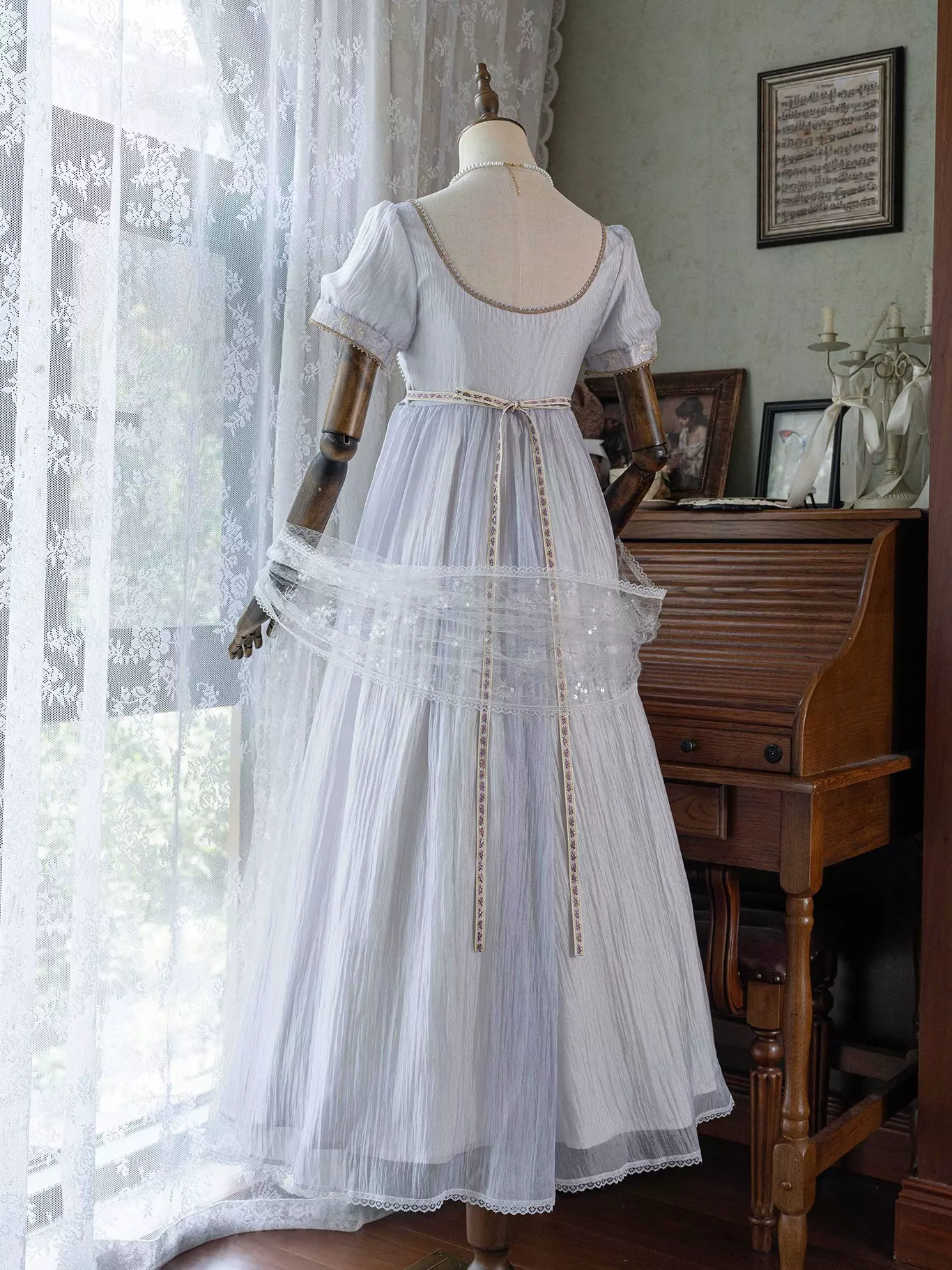 Back view on mannequin of purple Lolita Regency ball gown displaying square back neckline, empire waist, attached lace shawl overlay, gold decorative chains