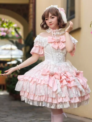 Pink off-shoulder sweet lolita dress with layered lace skirt and large pink bow details worn by model on European street