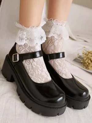 Black Academic Lolita Mary Jane platform pumps with round toe, ankle buckle strap, and chunky heel sole, styled on model wearing frilly lace ankle socks and white bedding background, oblique overhead view
