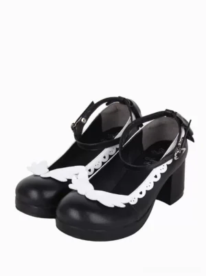 Angel wing lolita pumps front three-quarter view featuring black and white contrasting PU leather with scalloped white trim ornament and ankle buckle bow strap