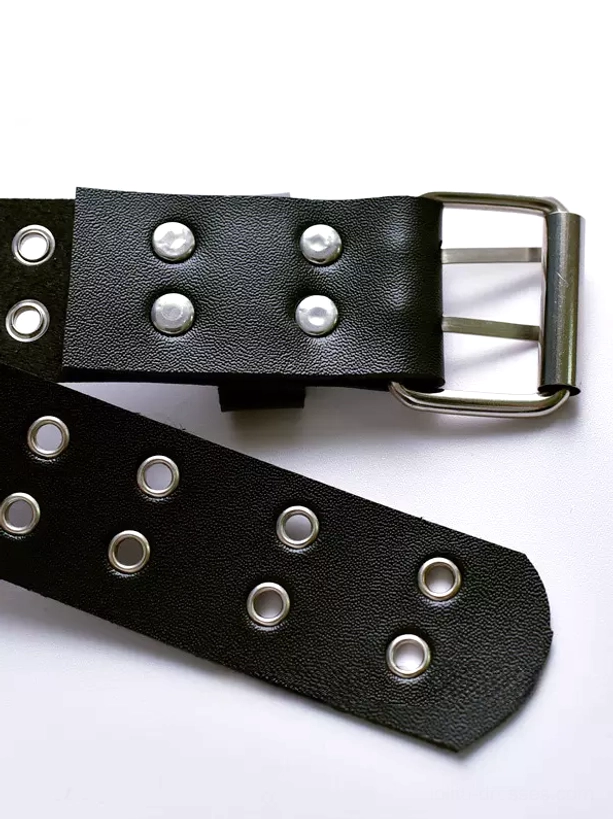 Separated components of black arm harness displaying silver metal buckle round eyelets and rivets in studio lighting