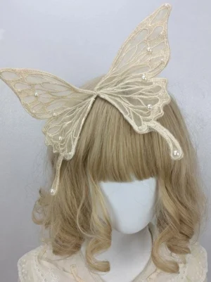 Beige butterfly lace hair clip with faux pearl trims and embroidered wing veins worn on blonde curly wig mannequin, side front view showcasing sheer mesh fabric detail