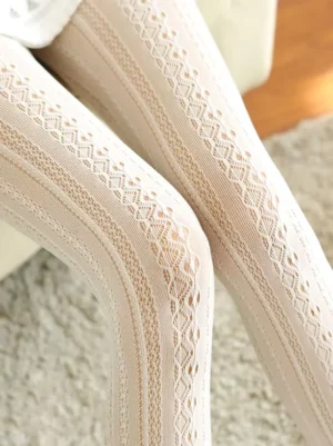 Beige lolita hosiery tights featuring geometric diamond stripe hollow lace pattern displayed on two legs indoor home setting showing delicate lightweight construction