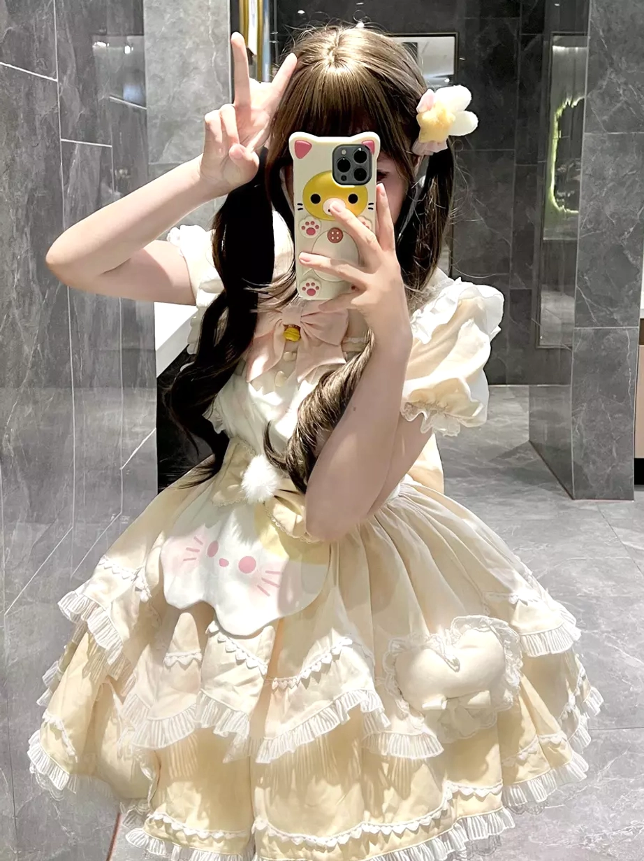 Beige sweet lolita cat dress front mirror perspective with puff short sleeves, ruffled hem, and cat face apron detail, model with flower hair clips marble setting
