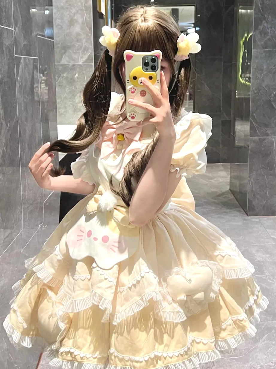 Beige sweet lolita cat dress side mirror view showing layered ruffled skirt construction, cat face front decor, model with flower hair clips marble aesthetic