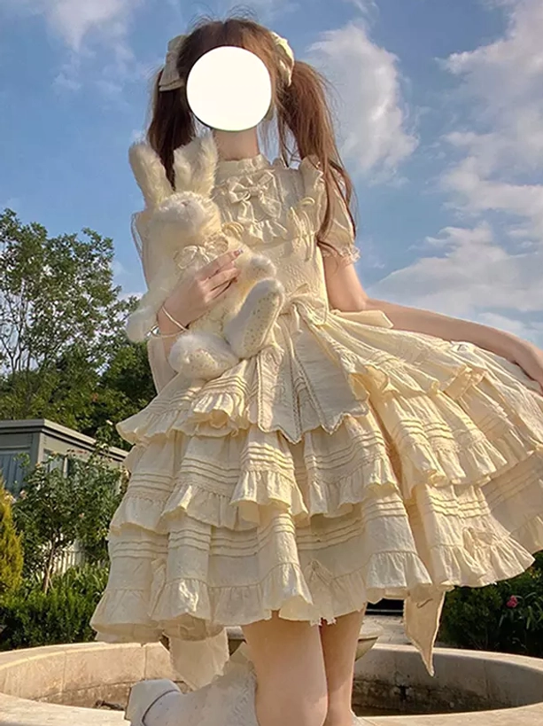 Beige sweet Lolita dress three-quarter front view flared tiered ruffled skirt short ruffled sleeves bow hair accessories