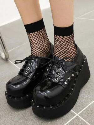 Black academic lolita platform shoes overhead front view with glossy pu leather studded edge lace-up design and round toe paired with fishnet ankle socks on tiled floor