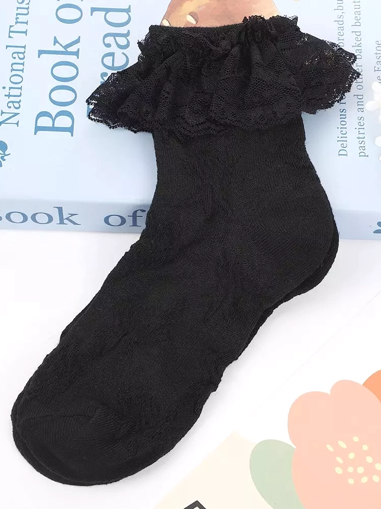 Single black ankle sock with thick ruffled lace cuff side view, styled with vintage book and floral prints for lolita fashion inspiration