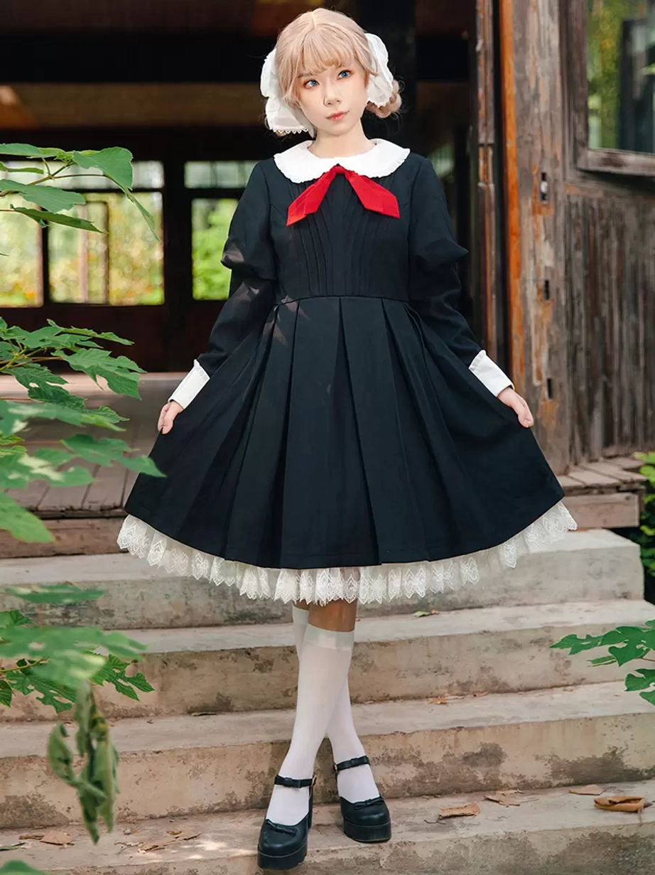 Model wearing classic black long-sleeve lolita dress outdoors on stairs with full front view, styled with white stockings and black platform shoes for authentic lolita coordination