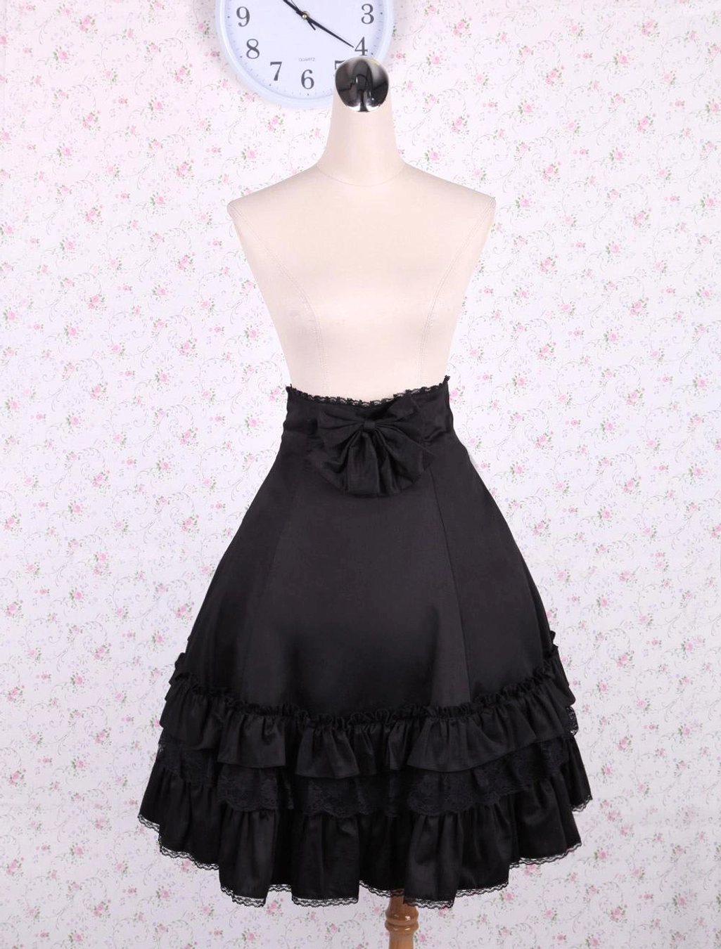 Black high-waisted lolita skirt front static pose displaying full ruffled lace hem volume and bow embellishment