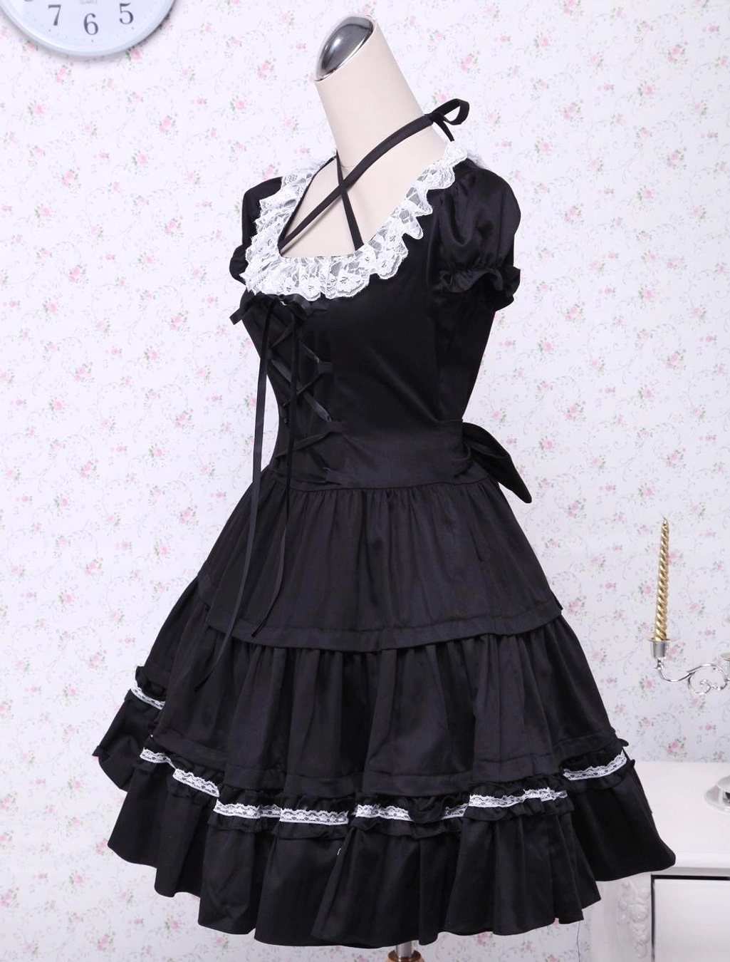 Black classic lolita dress left side view showing cross halter strap, fitted waist bow, and voluminous layered ruffled skirt construction
