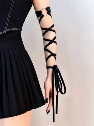 Black crisscross lace-up arm band worn on female model showing side view with crisscross leather straps and hanging tie tassels against black pleated skirt gothic lolita aesthetic