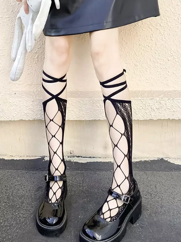 Black cross-strap fishnet knee-high socks with hollow diamond mesh pattern worn on lower legs and feet, paired with leather mini skirt and black platform Mary Jane shoes, outdoor street styling for lolita fashion coordination