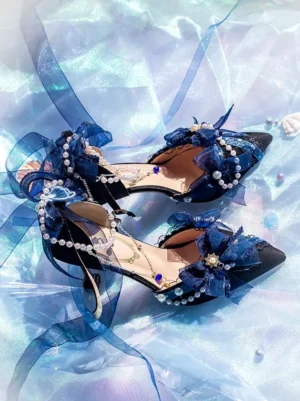 Black and dark blue Lolita high heels with pointed toe, blue bow decorations, pearl embellishments, and stiletto heel on iridescent satin background