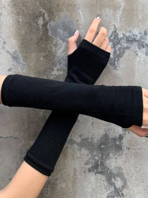 Black knitted fingerless arm warmers with ribbed cuff edges worn on two female arms showing matte finish and construction details