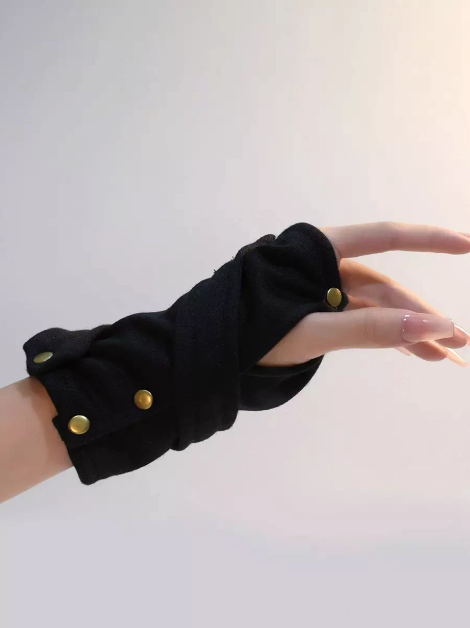 Close-up side view of black fingerless arm warmers on model's hand with light pink nail polish, showcasing wrapped fabric construction and multiple brass snap fasteners for gothic lolita accessory detail