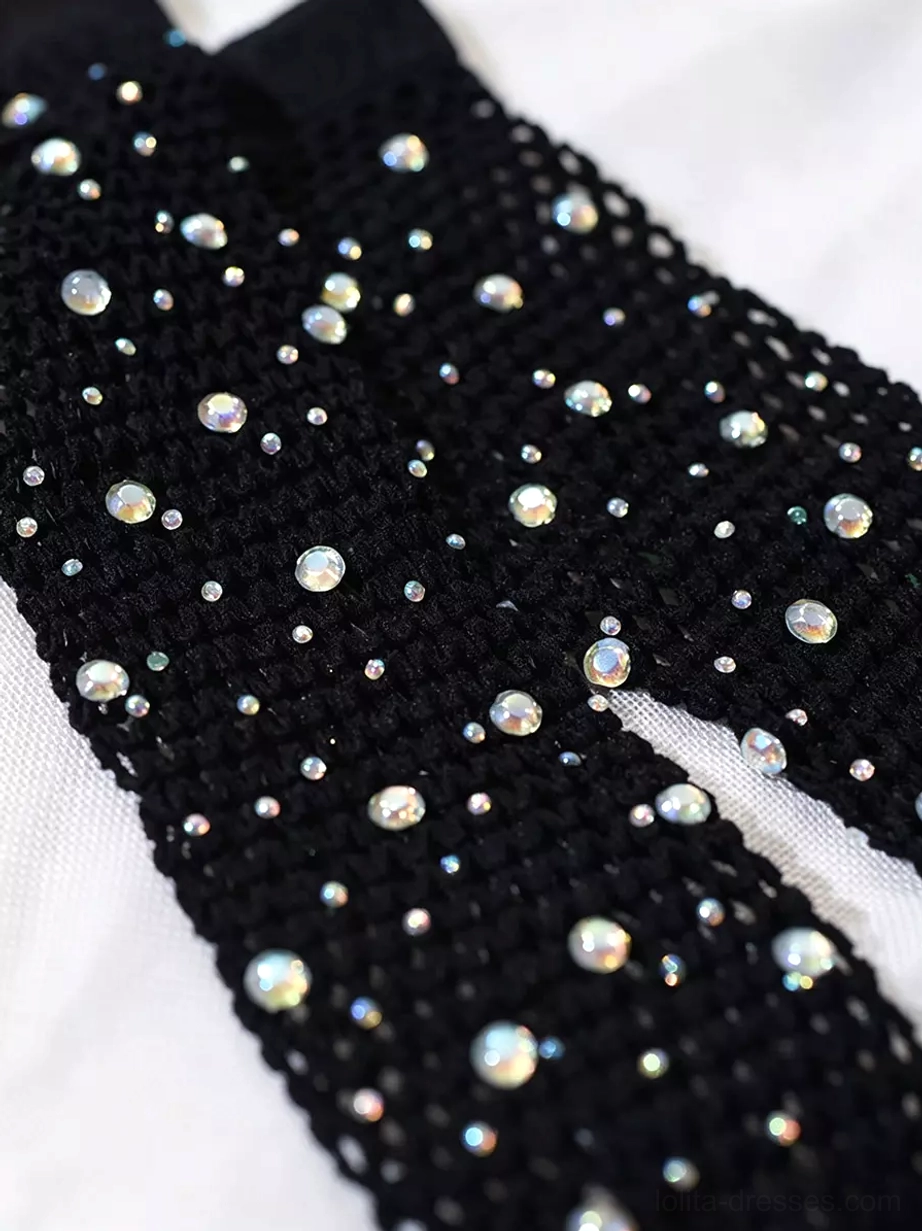 Flat-lay close-up of black fishnet glove fabric detail showing iridescent rhinestones on woven mesh base, highlighting craftsmanship and sparkle effect