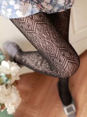 Black geometric lace lolita tights detailed close-up view showing intricate lace texture pattern on legs with floral skirt and grey flat shoes