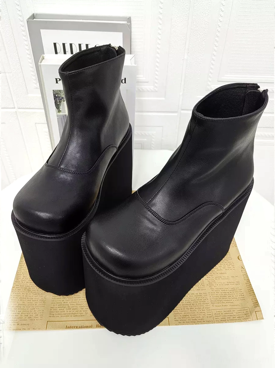 Black gothic lolita platform ankle boots three-quarter front view on decorative background showing round toe soft leather texture and high wedge platform