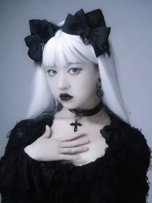 Black gothic lolita bow hair clips with heart cross charm worn on model with long white hair and gothic lace outfit, front three-quarter view
