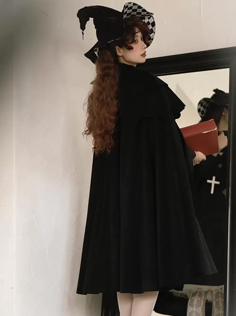 Back view of black Gothic Lolita cloak on model in front of mirror, showing floor-length cape silhouette and flowing fabric construction with long brown hair styling