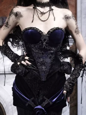Black gothic lolita corset bustier with crystal embellishments and tiered ruffles - close-up front view showing velvet fabric and detailed lace trim on tattooed model
