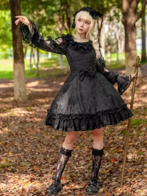 Black gothic lolita sleeveless dress with A-line ruffled skirt and lace sleeves on model holding cross scepter