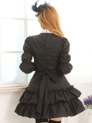 Black gothic lolita one-piece dress back view showing waist tie sash and layered ruffled skirt hem with puff long sleeves