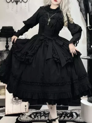 Black Gothic Lolita dress full front view showcasing shirred bodice, stand collar ruffles, layered ruffled skirt, and cross necklace accessory in indoor gothic studio