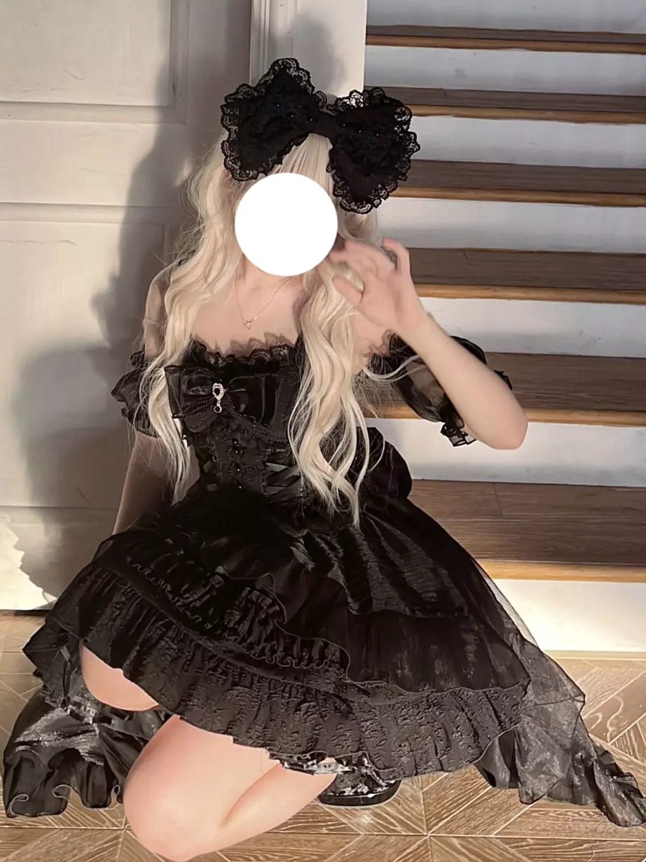 Back side view of black gothic lolita dress showing off-shoulder short sleeves ruffled skirt and sheer tulle train kneeling pose