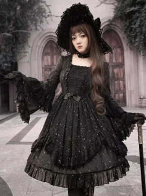 Black gothic lolita dress with sparkle hot stamping and tiered ruffles, front three-quarter view showing sparkly fabric and ruffled sleeves on model wearing wide witch hat and holding walking cane in church courtyard setting