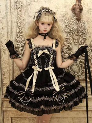 Black Gothic Lolita JSK dress front three-quarter view with beige bows, ruffled lace trim, pearl decorations, matching gloves and hair headdress on vintage carved wall background