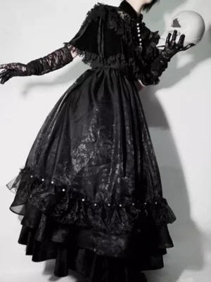 Black gothic lolita long dress with pearl-trimmed ruffle cape rear three-quarter view model wearing lace gloves with skull prop