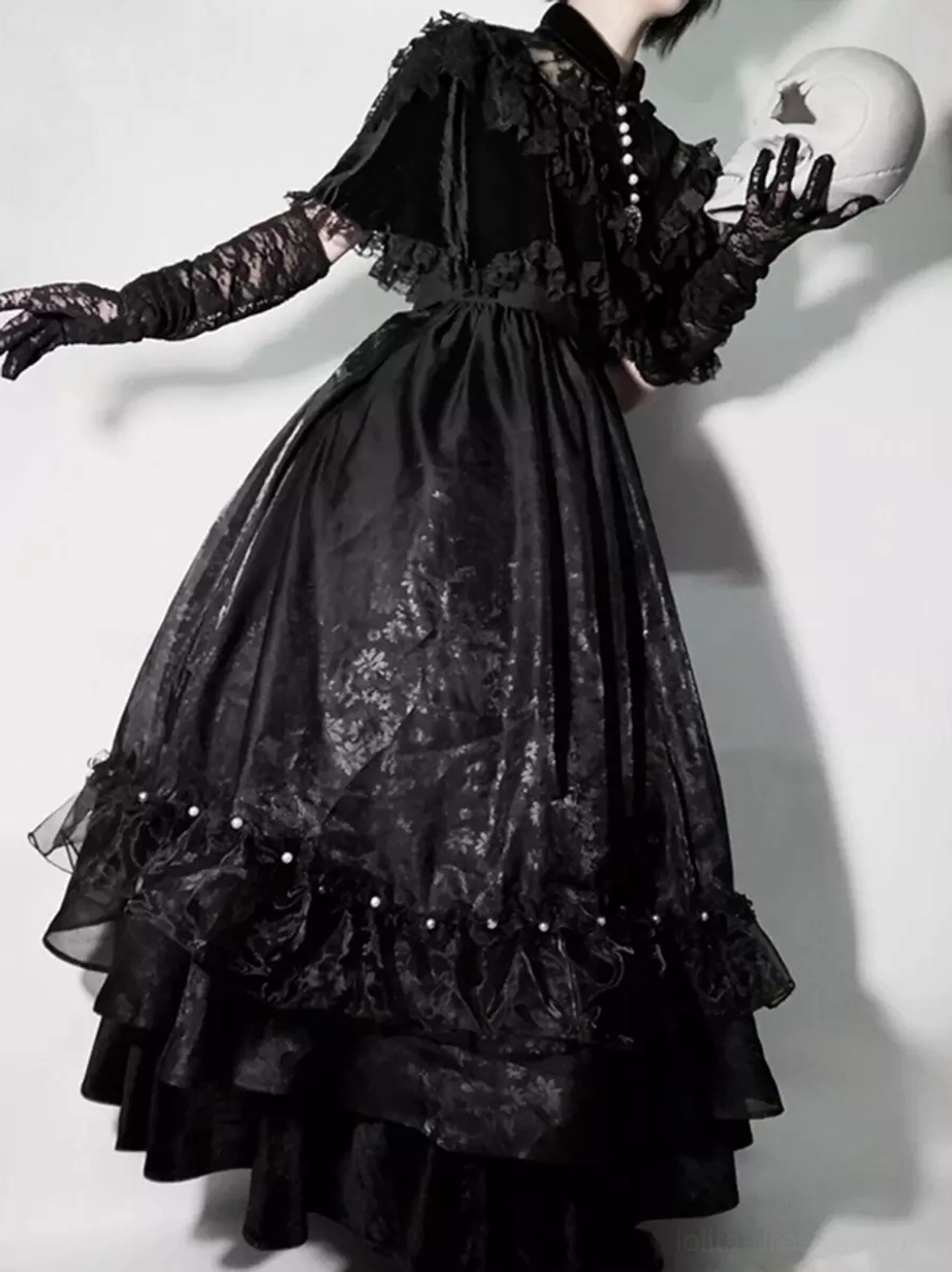 Black gothic lolita long dress with pearl-trimmed ruffle cape rear three-quarter view model wearing lace gloves with skull prop
