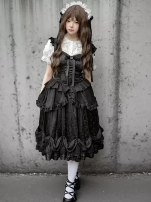 Black Gothic Lolita JSK dress full front view showing tiered ruffled skirt, corset bodice, lace trims and front bowknot decoration on model