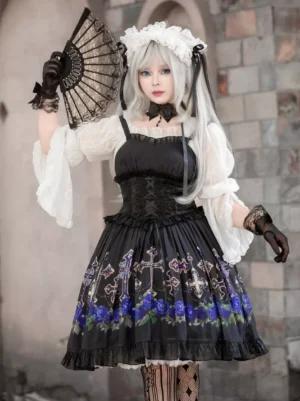 Black Gothic Lolita jumper dress with blue rose floral print, lace-up corset bodice, and ruffled lace hem worn by silver-haired cosplayer at vintage stone architecture backdrop
