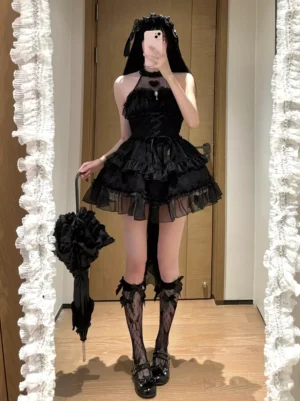 Black Gothic Lolita jumper dress with ruffled tiered tulle skirt, halter neckline, lace-up corset front, and heart embroidery detail - full-length front view on female model wearing lace stockings and black parasol