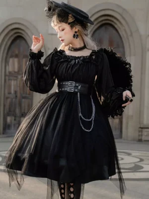 Black Gothic Lolita OP dress side view near vintage arched wooden doorway, displaying puff sleeves, hanging chain decorations at waist, midi tulle skirt, paired with black feather handbag accessory